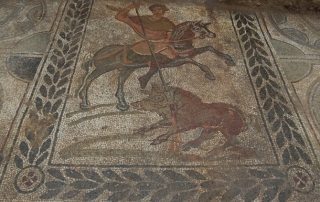 Mosaic floor with man on horse fighting a boar